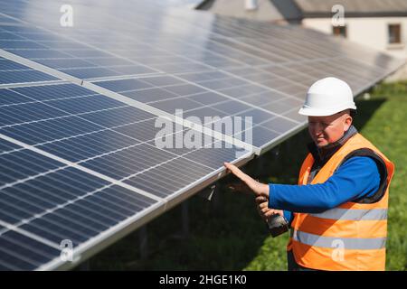 L'operatore di impianti solari con chiave elettrica nelle sue mani ispeziona i pannelli Foto Stock