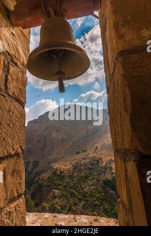 Una campana di cappella in grotta di Agia Sofia in un paesaggio di montagna selvaggia nell'isola di Creta, Grecia, Europa. Foto Stock