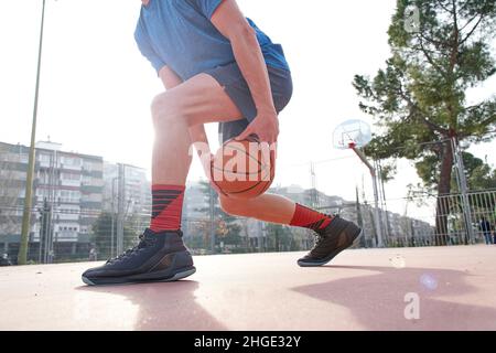 giovane uomo giocatore di basket strada dribbling con la palla sul campo, l'allenamento e l'attività concetto Foto Stock