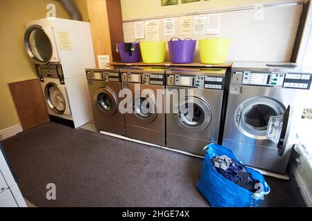 sacco di lavanderia pulita e lavatrice aperta in fila di lavatrici in una lavanderia a gettoni nel distretto di ambleside lake, cumbria, inghilterra, regno unito Foto Stock