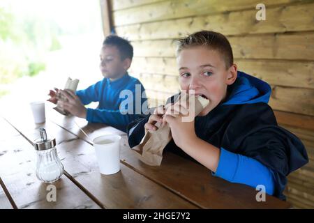 I ragazzi mangiano hot dog sulla terrazza del ristorante Foto Stock