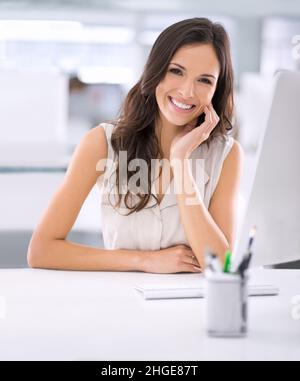 È fatta. Shot di una donna d'affari attraente seduta alla sua scrivania in un ufficio. Foto Stock