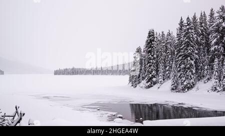 Maligne Lake, Canada - Dicembre 23 2021: Lago Maligne congelato circondato da boschi coperti di neve Foto Stock