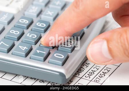Scatto corto di un uomo d'affari irriconoscibile che lavora le sue finanze con una calcolatrice e un documento nel suo ufficio Foto Stock