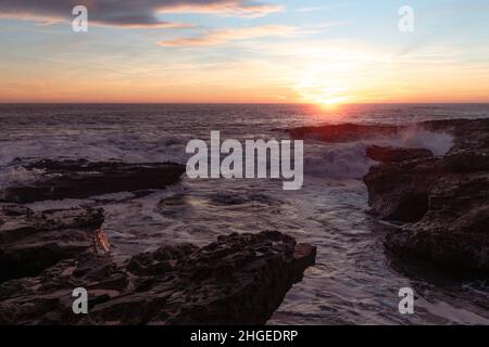 Bellissima alba sulla costa con le onde che si infrangono sulle rocce Foto Stock