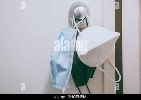 Gruppo di maschere chirurgiche appese alla maniglia della porta di casa. Primo piano di vista della maschera facciale durante il blocco della quarantena del coronavirus. Covid-19, salute, sanità, Foto Stock