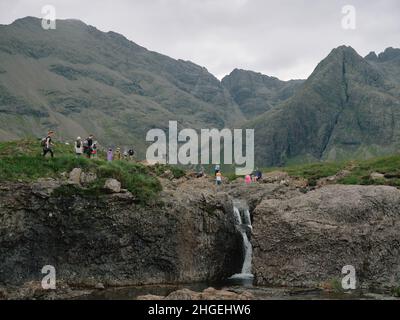 I turisti estivi alle famose piscine di Fairy una serie di cascate naturali a Glen fragle sull'isola di Skye Scozia Regno Unito - turismo overtourism Foto Stock