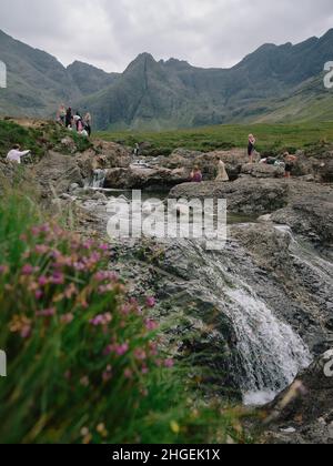 I turisti estivi alle famose piscine di Fairy una serie di cascate naturali a Glen fragle sull'isola di Skye Scozia Regno Unito - turismo overtourism Foto Stock