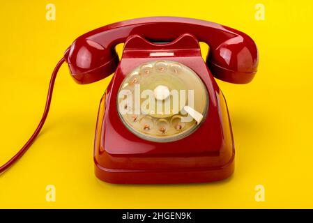 Vecchio telefono a quadrante rosso rotante isolato su sfondo giallo Foto Stock