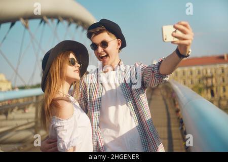 Coppia sorriso sul ponte. Turista divertirsi sulla vacanza avventura di viaggio sumer. I turisti felici scattano foto di se stessi sullo smartphone. Weeknd in Euro Foto Stock