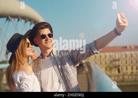 Coppia sorriso sul ponte. Turista divertirsi sulla vacanza avventura di viaggio sumer. I turisti felici scattano foto di se stessi sullo smartphone. Weeknd in Euro Foto Stock