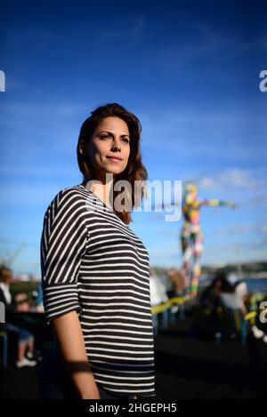 Bella giovane donna gode di un tonico gin e la vista dalla terrazza del Rio Maravilha Gastrobar, dove 'Maravilha', una scultura patchwork precedente Foto Stock