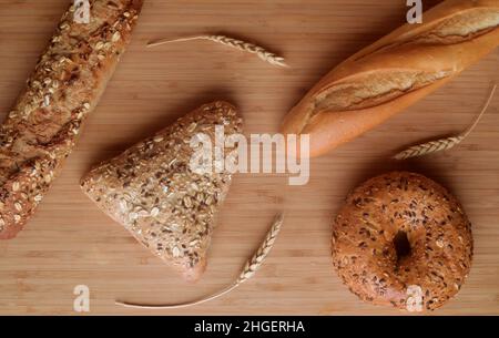 Diversi tipi di pane, dolci freschi nella panetteria. Pane con semi di sesamo, cereali, semi. Forme e tipi diversi di rotoli. Spighe di grano su un w Foto Stock