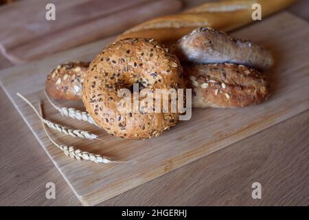 Diversi tipi di pane, dolci freschi nella panetteria. Pane con semi di sesamo, cereali, semi. Forme e tipi diversi di rotoli. Spighe di grano su un w Foto Stock