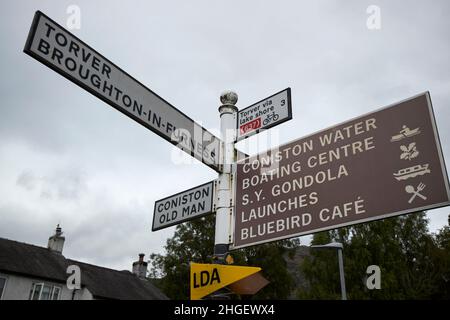 metal vecchio road sign tradizionale a coniston per il torver broughton-in-furness e coniston vecchio uomo locali amenità lake district, cumbria, inghilterra, regno unito Foto Stock