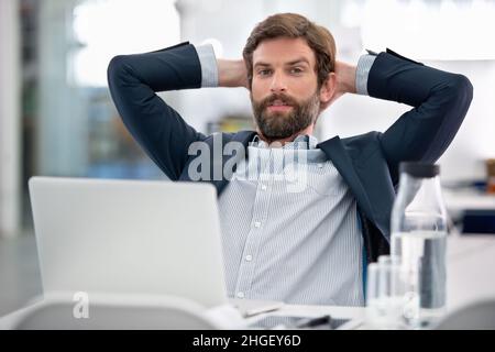 Prende molto sul serio il suo lavoro. Scatto di un giovane uomo d'affari seduto alla sua postazione di lavoro in un ufficio. Foto Stock