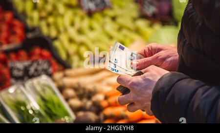 L'uomo prende banconote in euro dal portafoglio sul mercato Foto Stock