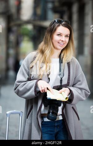 Bionda ragazza ordinaria che tiene la brochure in mani Foto Stock