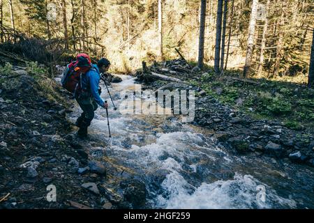 Fiume in montagna con pietre, un turista attraversa il fiume Foto Stock