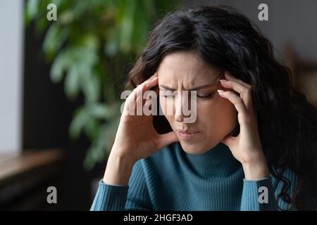 Una donna d'affari infelice soffre di forte mal di testa toccare templi esausto dallo stress sul posto di lavoro Foto Stock