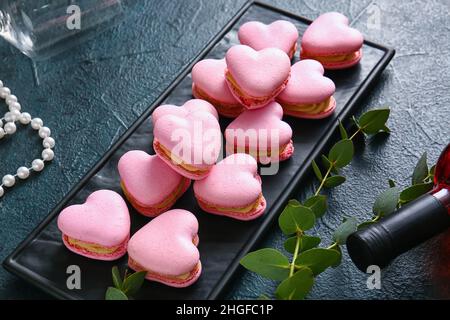 Bordo con gustosi macaroni a forma di cuore su sfondo nero Foto Stock