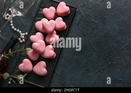 Bordo con gustosi macaroni a forma di cuore su sfondo nero Foto Stock