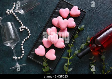 Sali a bordo con gustosi macaroni a forma di cuore e vetro su sfondo nero Foto Stock