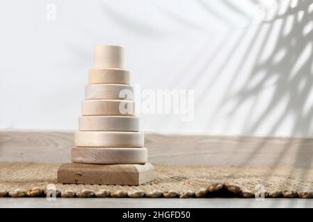 Piramide di legno su un tappeto di vimini, ombra da una palma. Spazio vuoto per il testo. Foto Stock