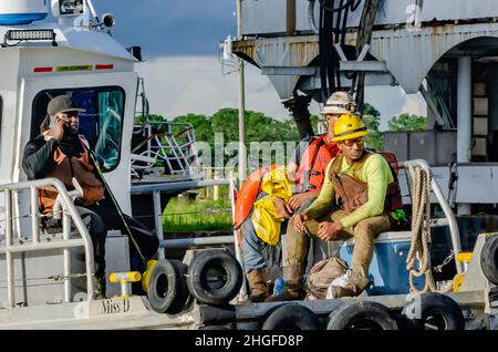 I lavoratori si riuniscono mentre la Tugboat Miss D arriva a riva, 1 luglio 2021, a Bayou la Batre, Alabama. Foto Stock