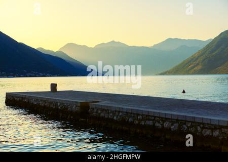 Molo di pietra e baia d'acqua circondata da montagne. Spettacolare laguna con montagne Foto Stock