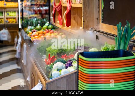 Mercato locale fresco con frutta e verdura sugli scaffali. Carrelli di shopping. Umidificatore per green. Foto Stock