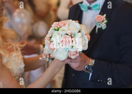 Lo sposo in un vestito dona alla sposa un bouquet di nozze bianco e pesca  Foto stock - Alamy