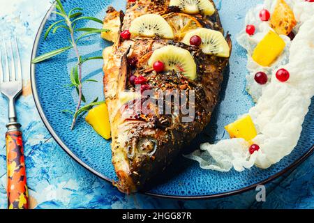 Carpa di pesce al forno con frutta, bacche e spezie. Foto Stock