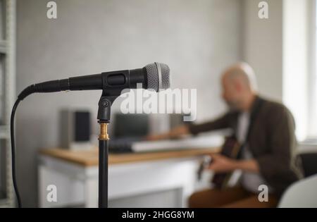 Primo piano del microfono sul rack in piedi in studio di musica su sfondo di musicista. Foto Stock