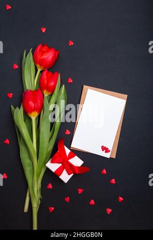 Confezione regalo, bianco, fiori e un cuore di carta su sfondo nero per San Valentino. Festa della mamma. Buon compleanno Foto Stock