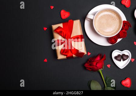 San Valentino sfondo. Regalo, rose di caffè, candele, cuori su sfondo nero. Concetto di giorno di San Valentino. Disposizione piatta, Foto Stock