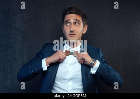 Bel giovane uomo d'affari con cravatta ad arco su sfondo grigio. Foto Stock