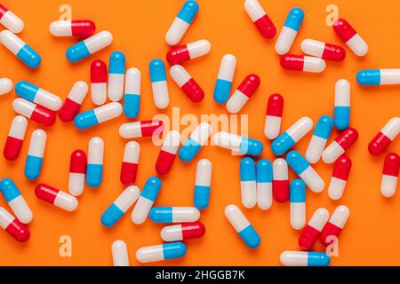 Composizione creativa con pillole colorate su sfondo arancione. Concetto minimo. Foto Stock