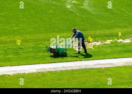 Kiev, Ucraina - 28 aprile 2021: Un uomo rasa il prato nello stadio di calcio alla vigilia della partita. Foto Stock