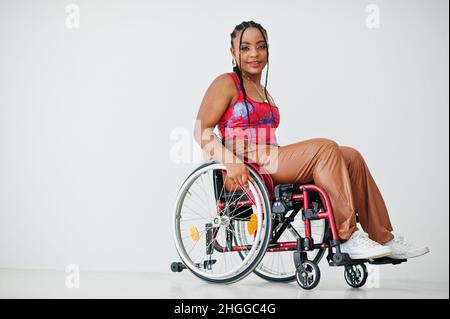 Giovane donna afroamericana disabile in sedia a rotelle contro parete bianca. Foto Stock