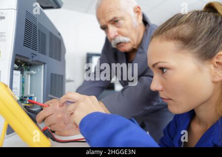 giovane tecnico femminile che utilizza il multimetro sull'apparecchio Foto Stock