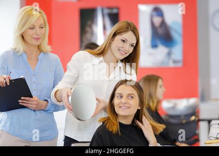 Insegnante aiuta gli studenti a formazione per diventare parrucchieri Foto Stock