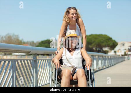 amico e donna in sedia a rotelle su un molo Foto Stock