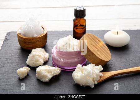 Fare bodywhip anche noto come burro corpo, crema idratante per la cura della pelle. Ingredienti su sfondo legno: Burro di karité, olio di cocco solido, oli essenziali. Foto Stock