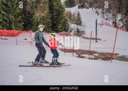 Ragazzo imparando a sciare, allenandosi e ascoltando il suo maestro di sci sulla pista in inverno Foto Stock