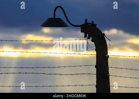 Recinzione di filo spinato e una lampada all'ex campo di concentramento e sterminio nazista di Auschwitz II-Birkenau a Oswiecim, Polonia, il 3 gennaio 2022. Foto Stock