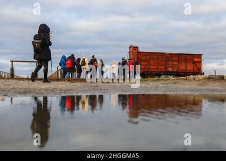 I visitatori si trovano accanto a un'originale carrozza ferroviaria utilizzata per le deportazioni presso l'ex campo di concentramento e sterminio nazista di Auschwitz II-Birkenau a Oswiecim, in Polonia, il 2 gennaio 2022. Foto Stock
