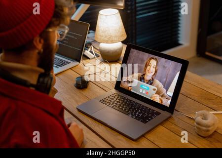 Uomo che ha incontri online con una collega, mentre lavora a casa Foto Stock