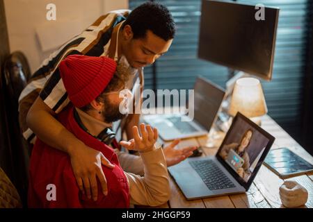 Elegante coppia gay che ha una videochiamata con una collega Foto Stock