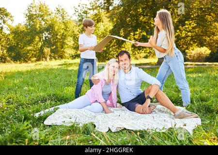 I bambini tengono il tetto sopra le loro teste dai genitori come simbolo per la propria casa e edificio della casa nel parco Foto Stock